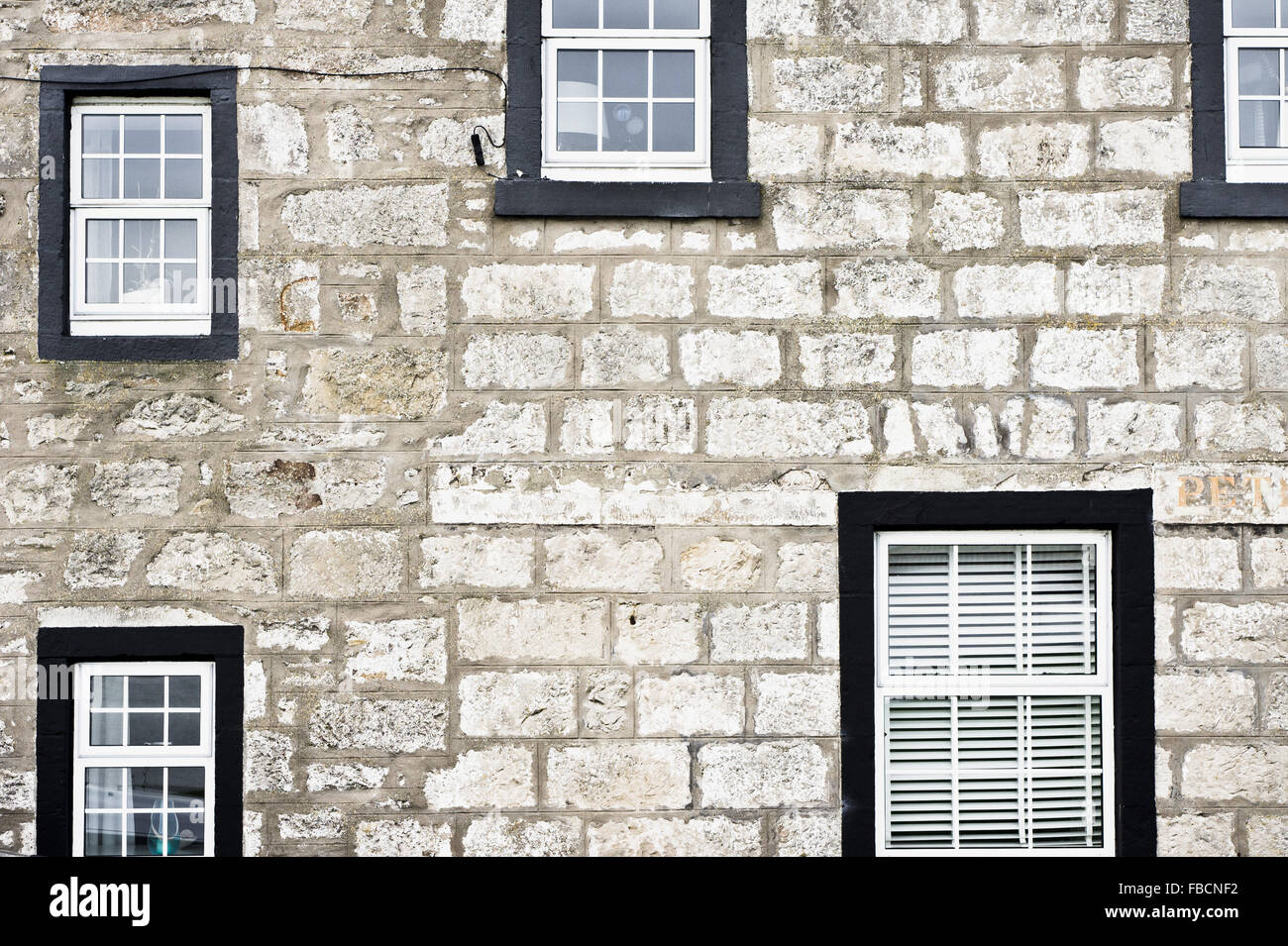 Des fenêtres de différentes tailles dans une maison en pierre Banque D'Images
