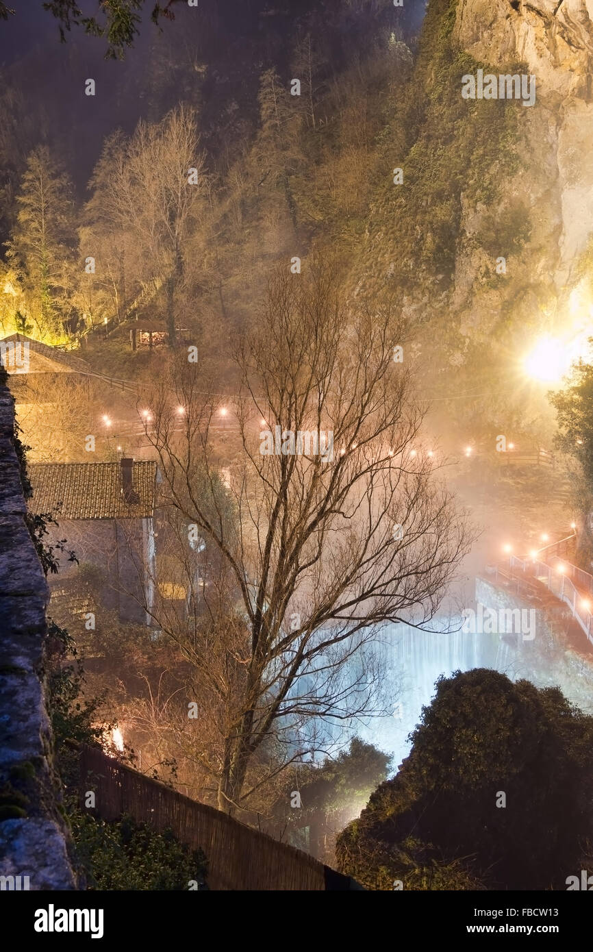 Scène de nuit de brouillard. Plutôt impressinistic avec de nombreuses sources de lumière et brouillard sur la cascade. Village de montagne, Equi Terme, ita Banque D'Images