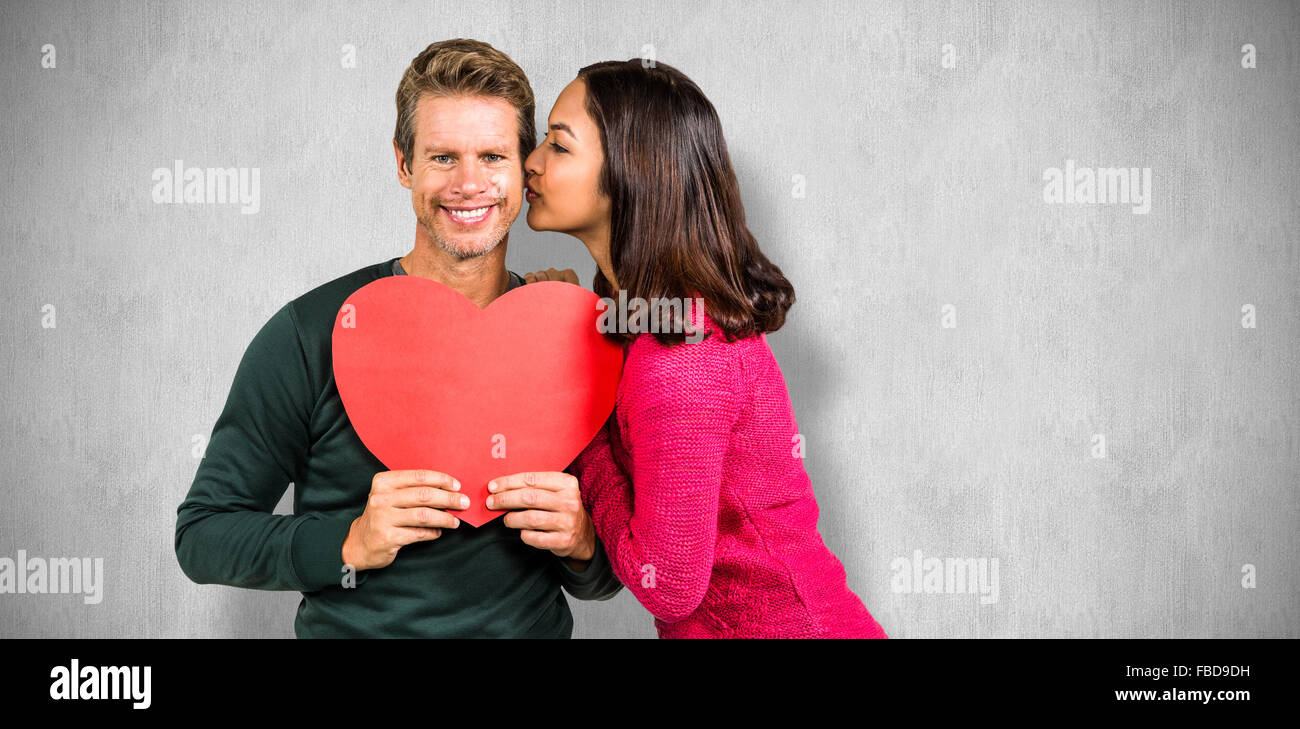 Image composite de woman kissing boyfriend avec forme de coeur rouge Banque D'Images