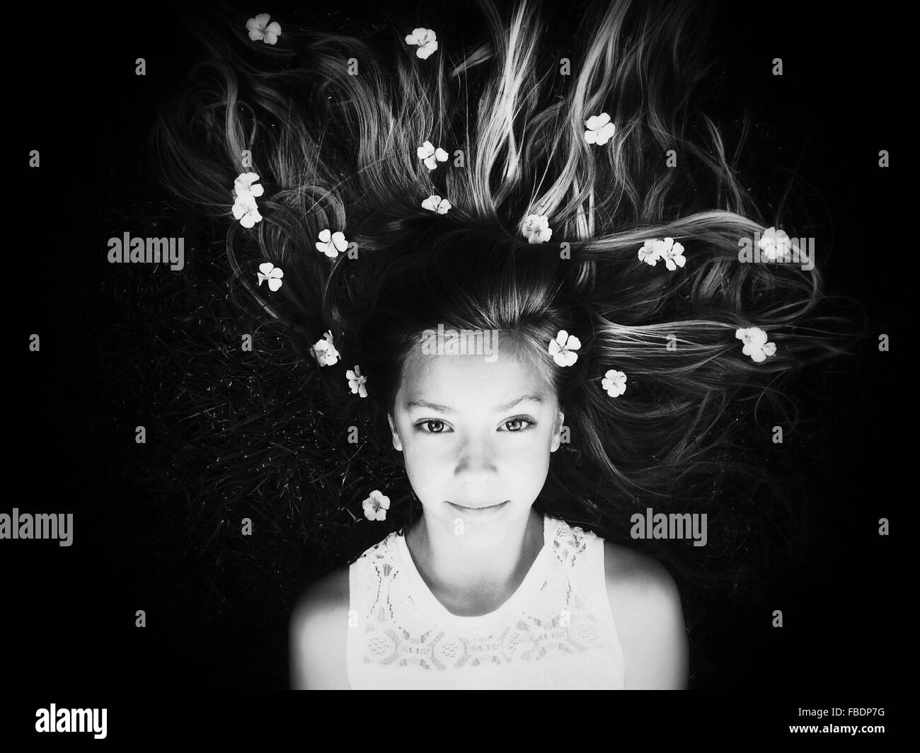 Portrait de jeune fille couchée avec des fleurs dans les cheveux Banque D'Images