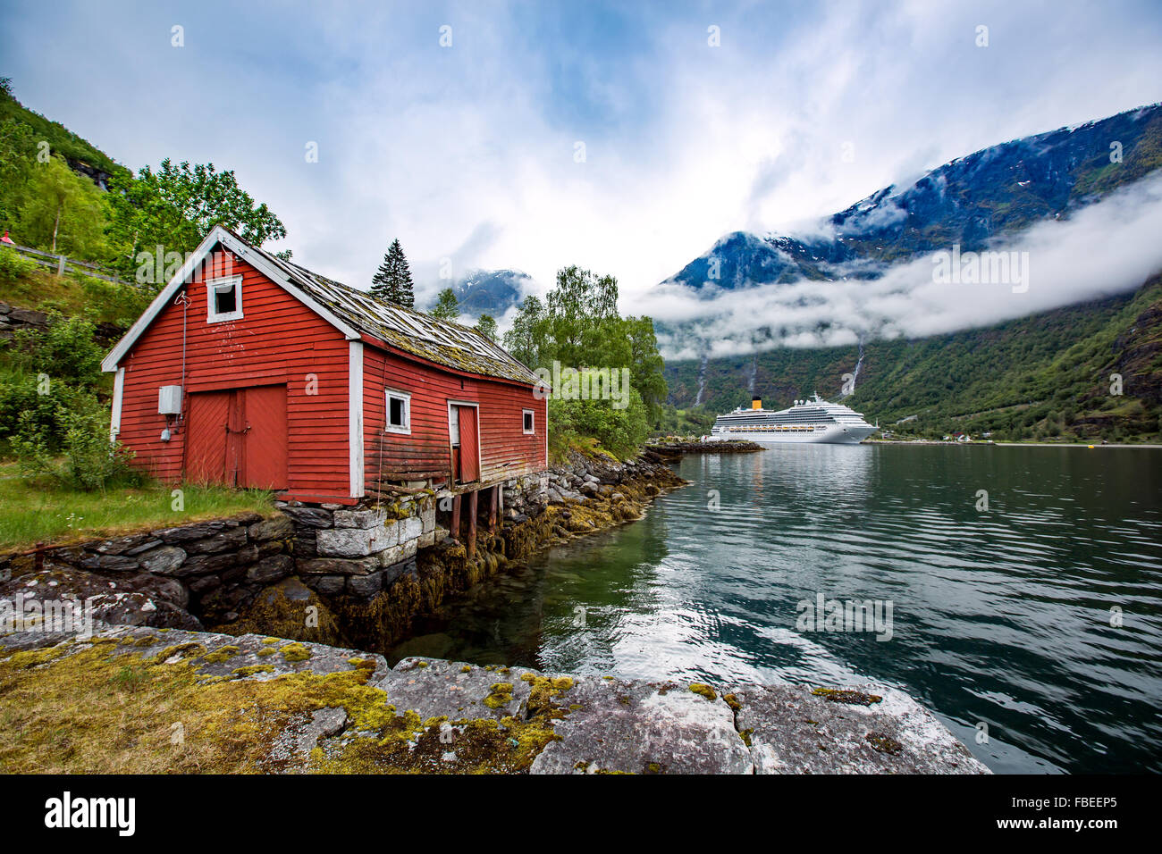 La Norvège paysage, la maison sur la rive du fjord dans l'arrière-plan d'amarrage bateau de croisière. Banque D'Images