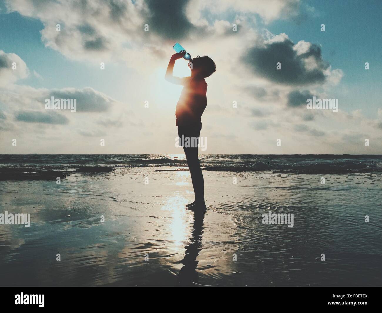 Vue latérale d'Homme debout et l'eau potable à bord de mer contre Ciel nuageux Banque D'Images