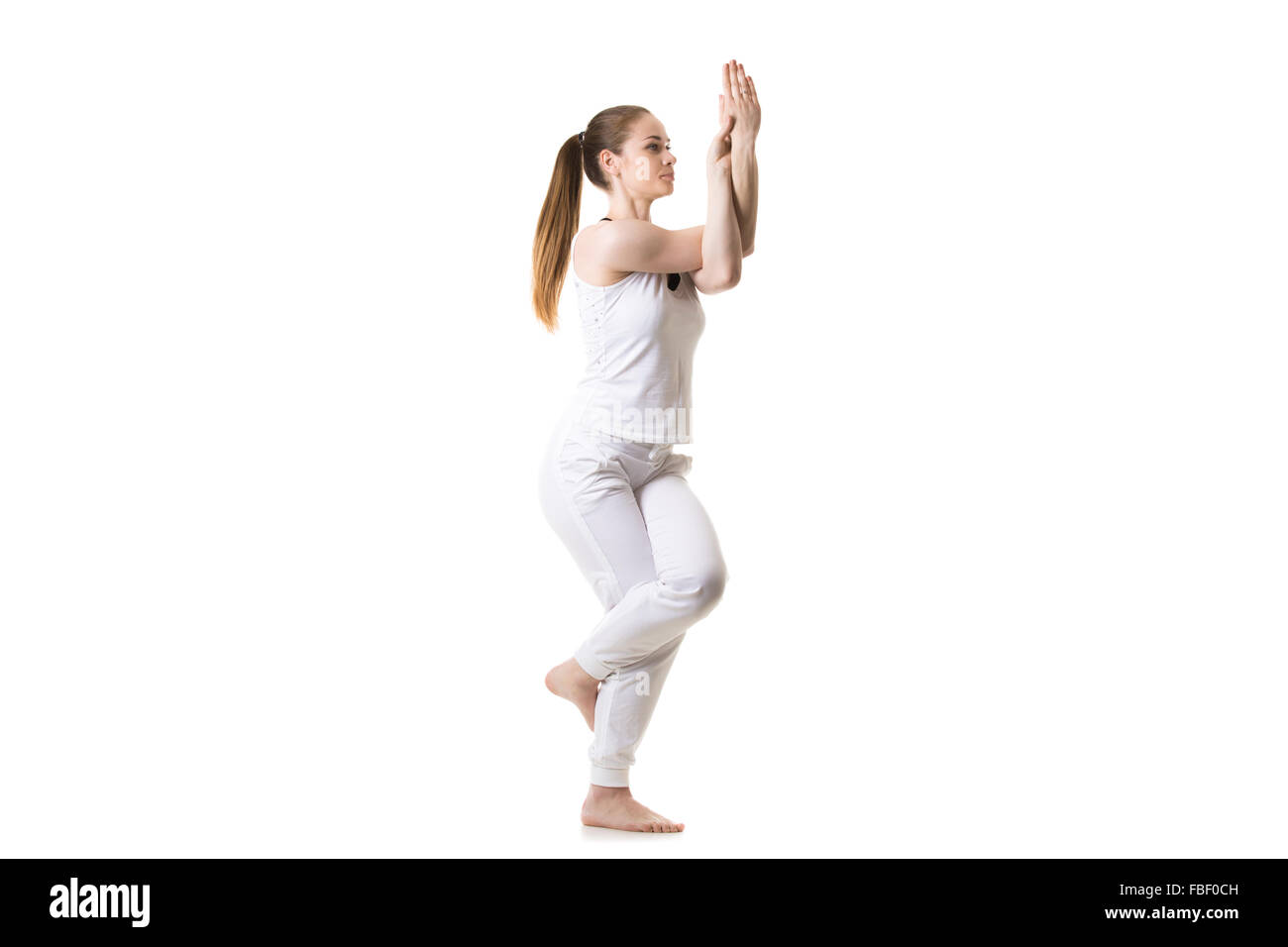 Beau Modèle de remise en forme pratique le yoga ou Pilates, debout dans le yoga posture de l'Aigle, Garudasana, trois quarts vue, studio shot, est Banque D'Images