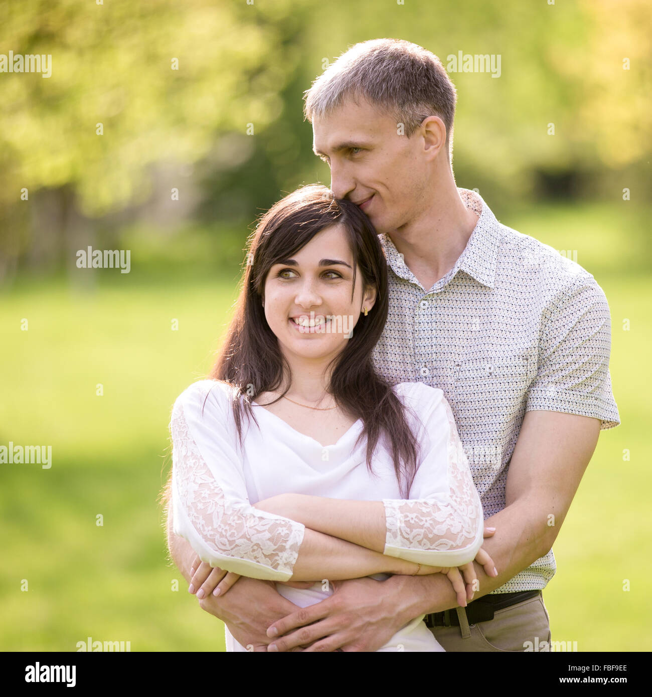 Couple d'amoureux sur une date, jeune homme de câliner tendrement avec son happy smiling girlfriend, de lui embrasser les cheveux avec expr Banque D'Images