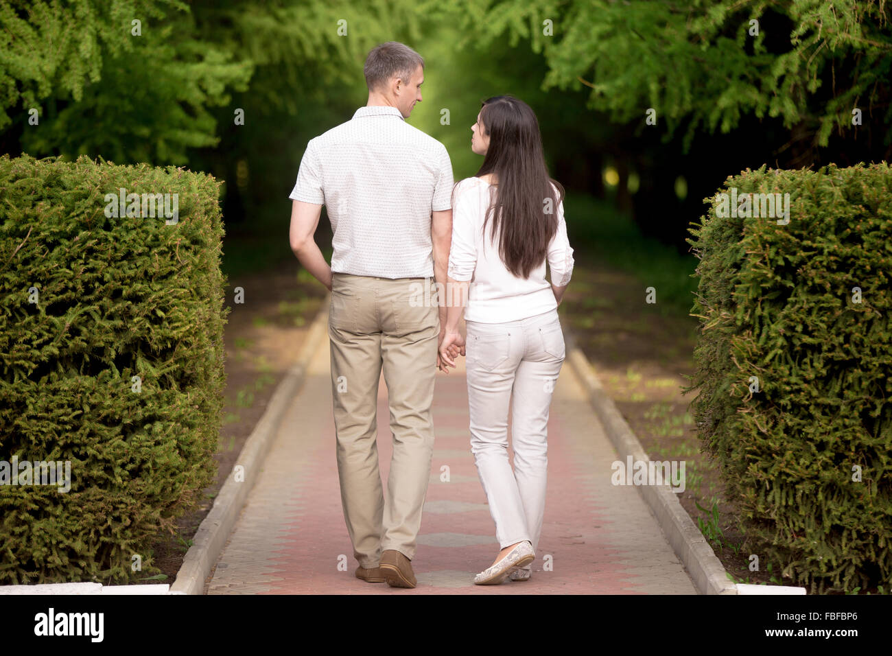 Couple in love walking in park holding hands, séduisant jeune homme et femme sur la date, regarder, parler, longueur totale Banque D'Images