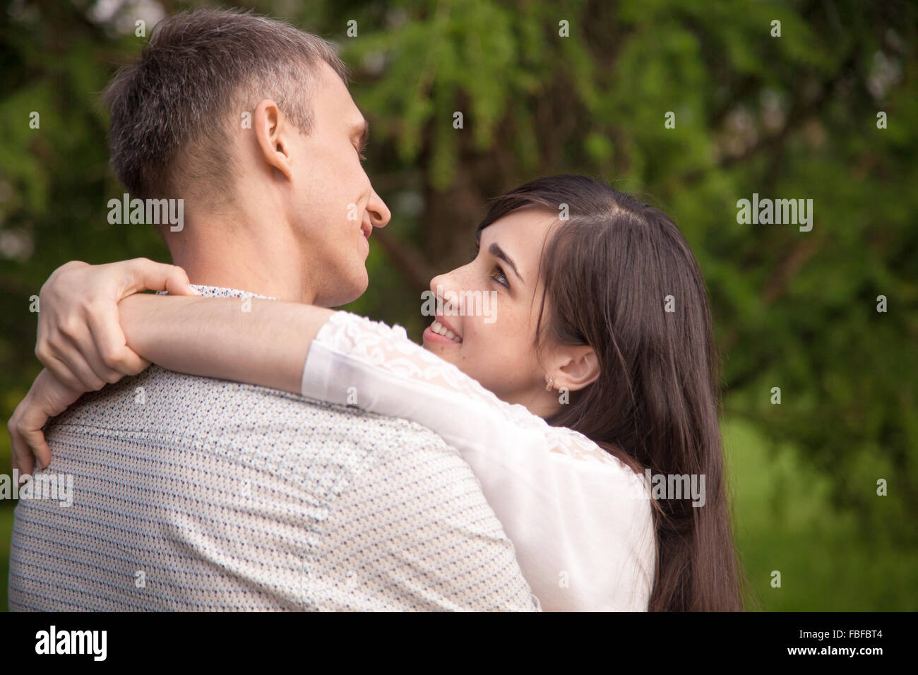 Couple d'amoureux sur une date dans le parc, debout face à face, parler, tendrement enlacés, young happy smiling woman joyeusement hugg Banque D'Images