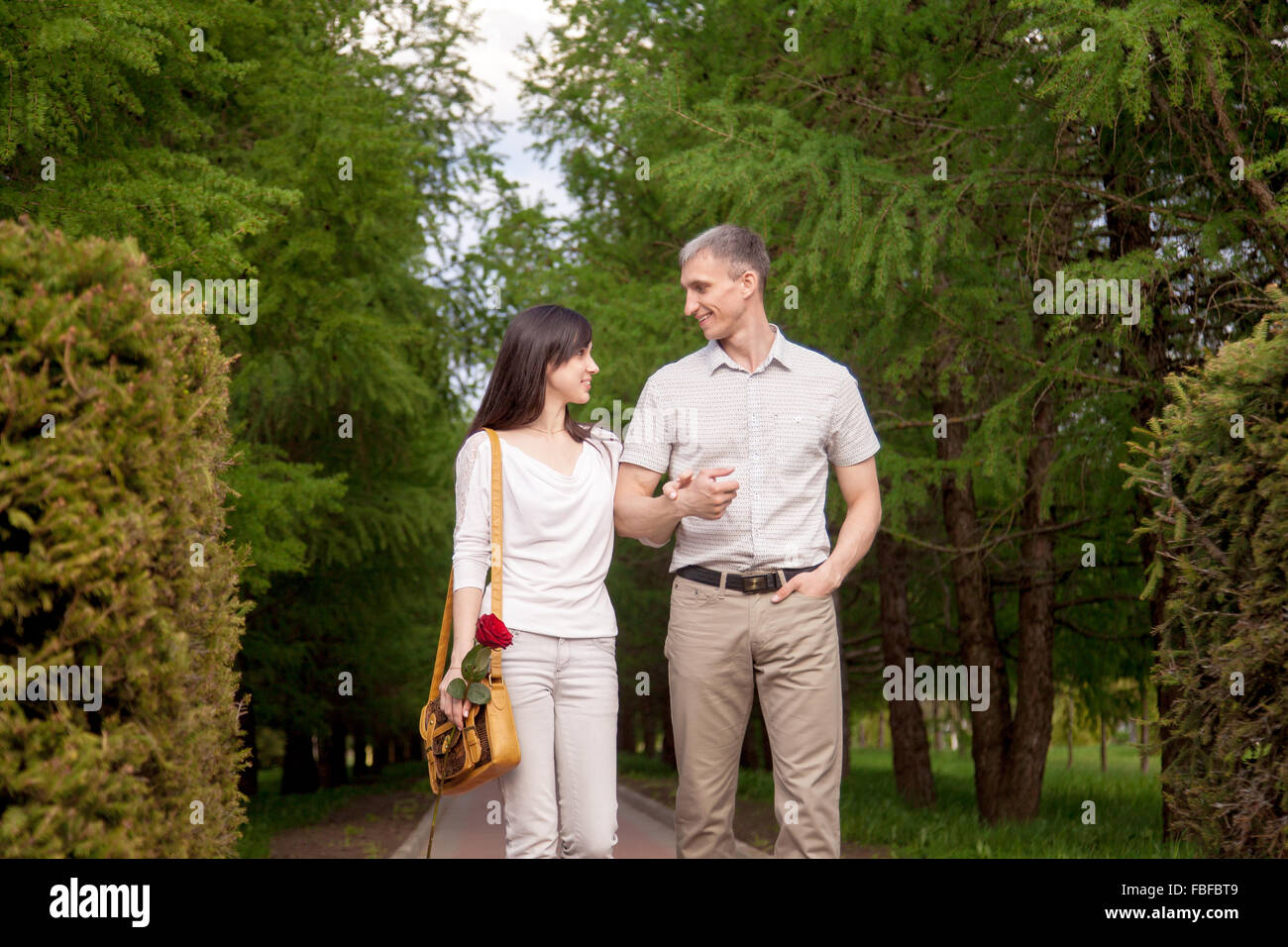 Portrait de couple d'amoureux à marcher ensemble sur une date dans le parc en été, à l'un de l'autre, jeune homme tenant son beautifu Banque D'Images