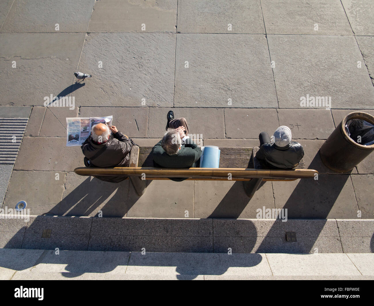 En train de lire le journal et regarder le monde passer à Londres sur un banc Banque D'Images