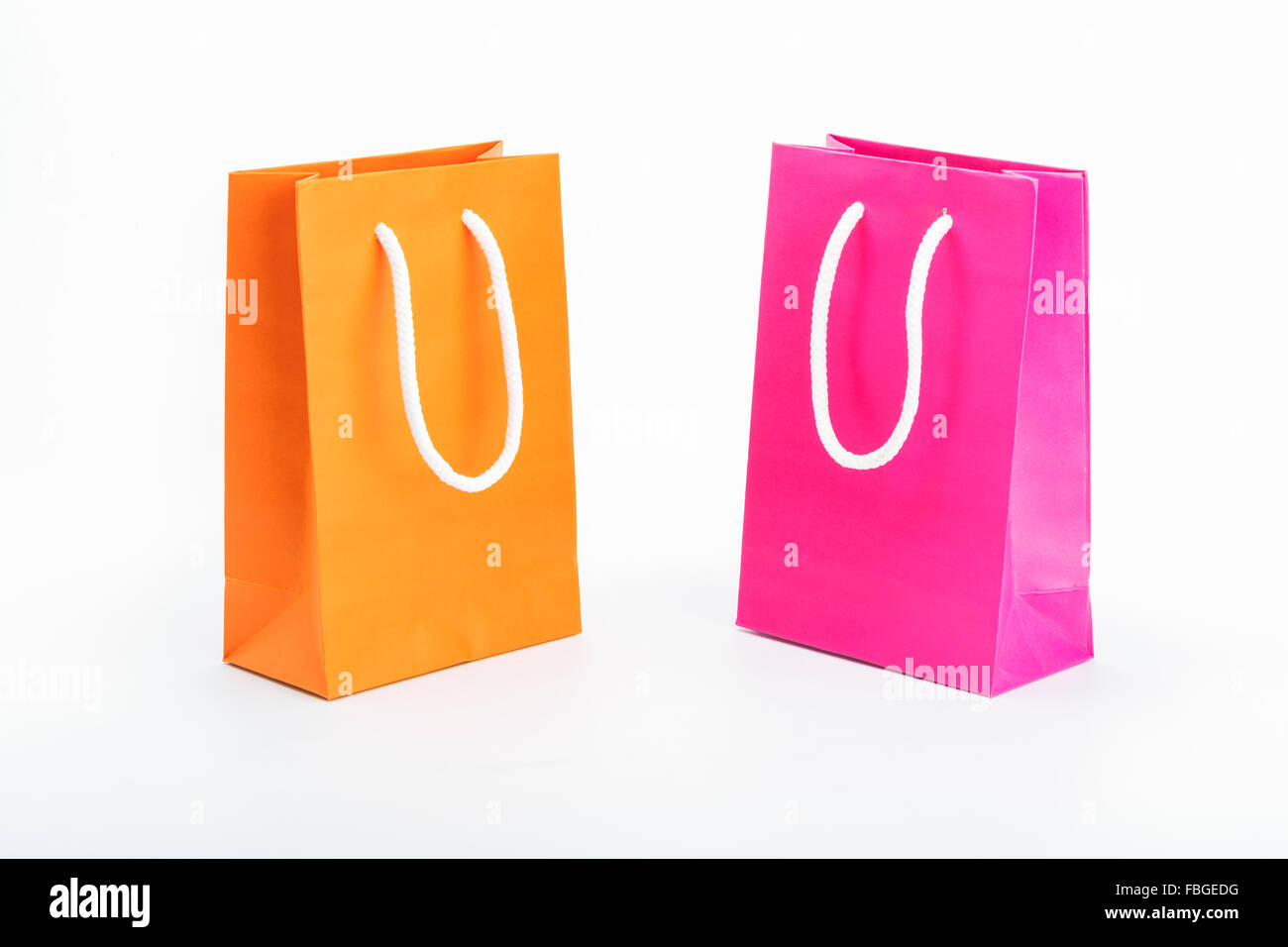 Des sacs de papier, orange et rose sur fond blanc Banque D'Images