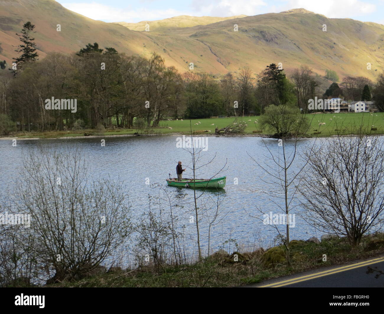 Un pêcheur à la pêche de mouche sur Ullswater dans le Lake District. Banque D'Images