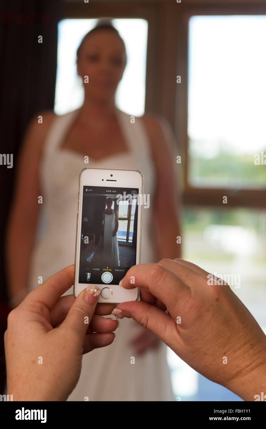 Une demoiselle d'honneur prend une photo d'une épouse sur un iPhone d'Apple. Banque D'Images