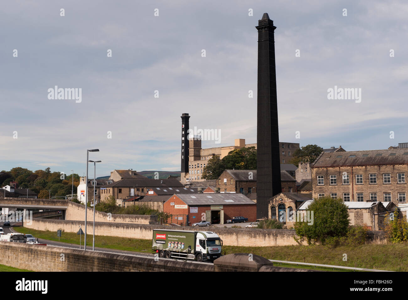 Voir l'ensemble du trafic sur une route en direction de secours Bingley650,  tall historique cheminées noires de 2 usines victoriennes - l'un est  l'usine de Damart France, FR, UK Photo Stock -