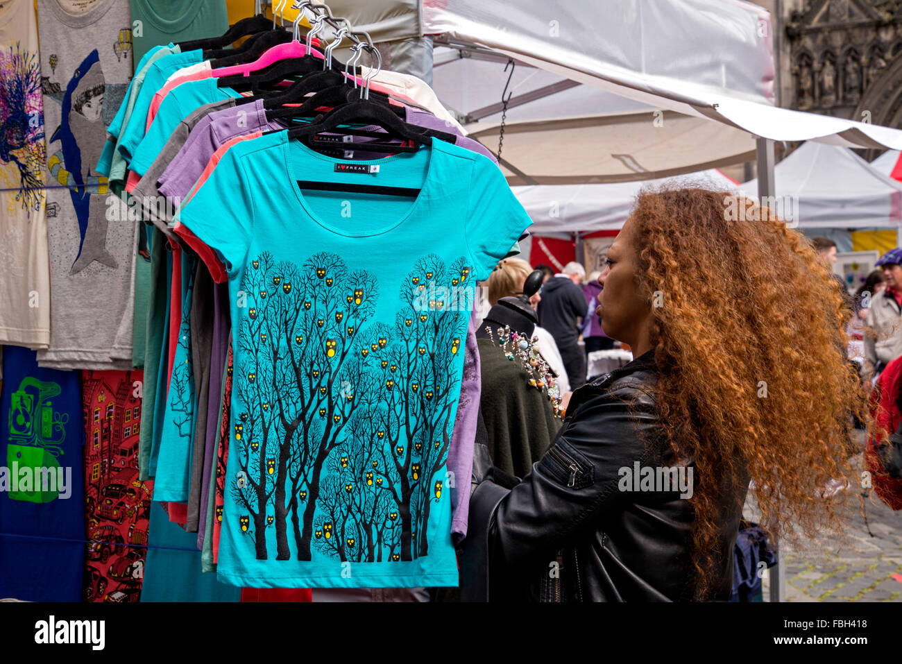 Une femme de couleur de cheveux rouge examine t tee shirts sur un étal dans la place du Parlement pendant le Festival d'Édimbourg. Banque D'Images