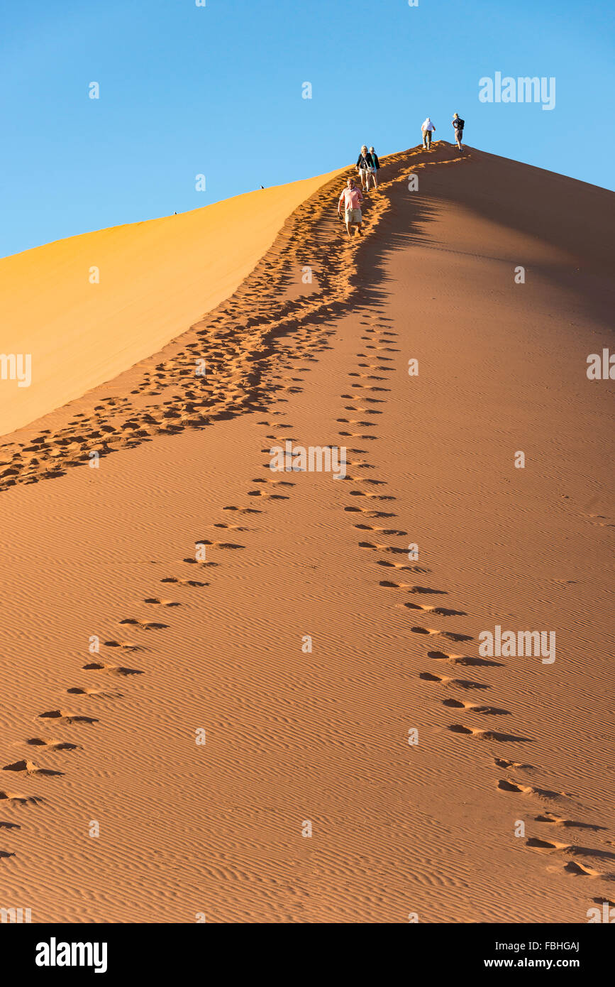 Escalade les touristes, des dunes de sable Sossusvlei, Désert du Namib, le parc de Namib Naukluft, Région Hardap, République de Namibie Banque D'Images