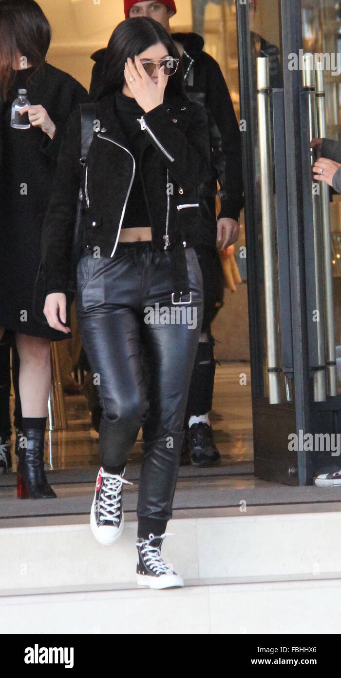 Kylie Jenner couvre son visage alors qu'elle quitte Barneys New York à  Beverly Hills car elle montre son estomac dans un pull cropped noir et veste  en cuir noire avec une paire