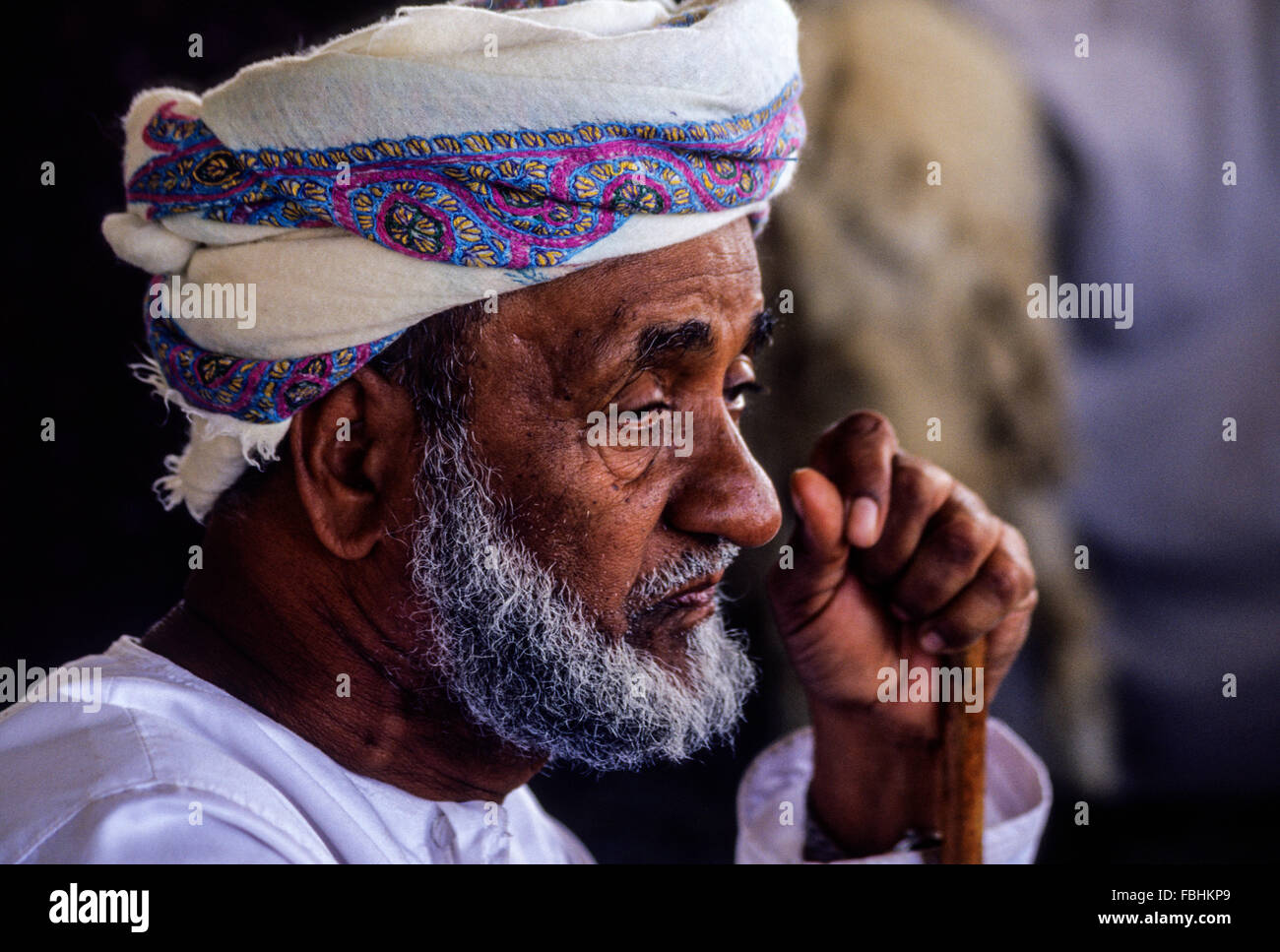 L'Oman. Vieil homme sérieux portant son Msarr (Massar), avec bâton de marche. Banque D'Images