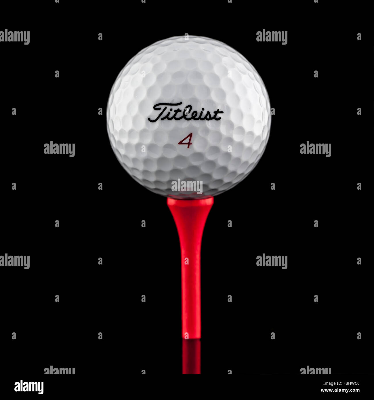 Balle de Golf Titleist sur un Tee rouge sur fond noir Banque D'Images