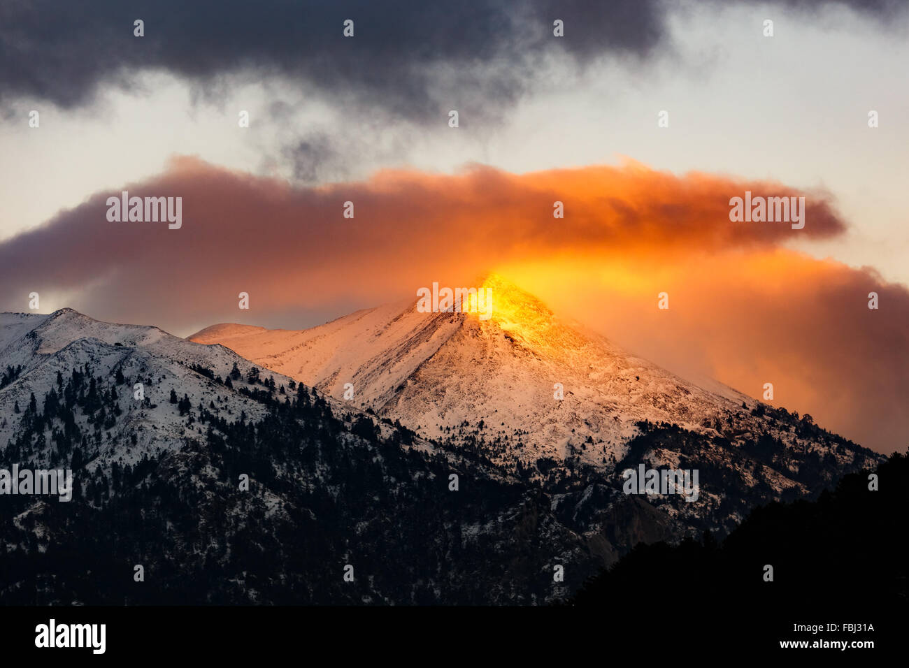 Paysage de montagne d'hiver à l'aube ou au coucher du soleil avec des rayons de lumière dorée du soleil sur le pic de production en Grèce Banque D'Images