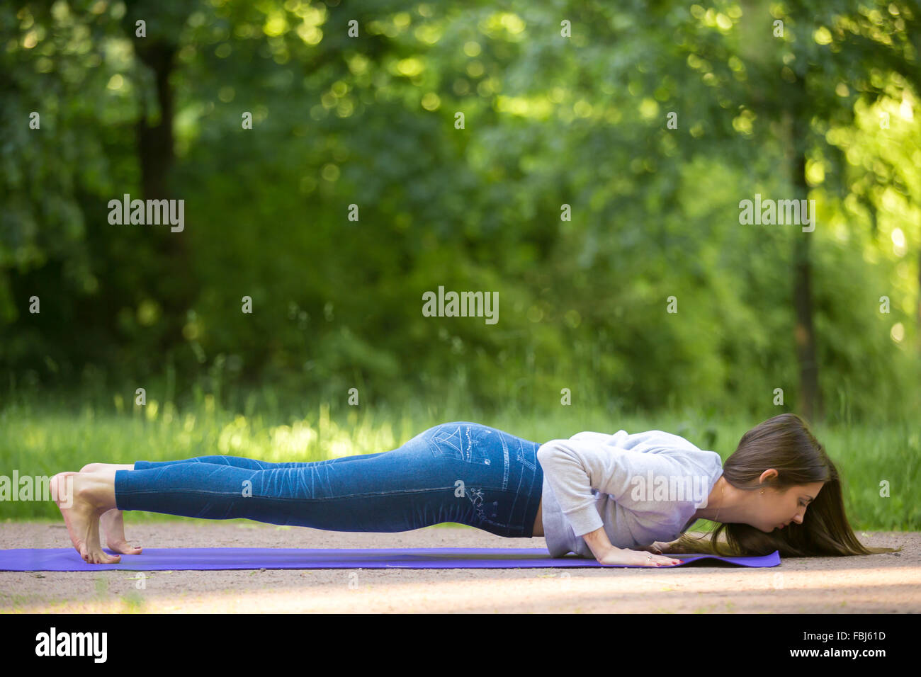 Belle jeune femme sportive travaillant sur rue, faire la formation de force, crossfit sur bleu mat dans Park Alley, push-ups, chatu Banque D'Images