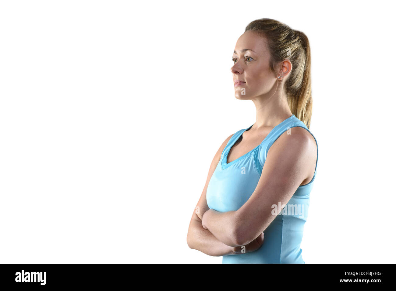 Taille Portrait of Smiling Woman Wearing Athletic Light Blue Tank Top standing in front of Gray Background Studio avec armoiries Banque D'Images