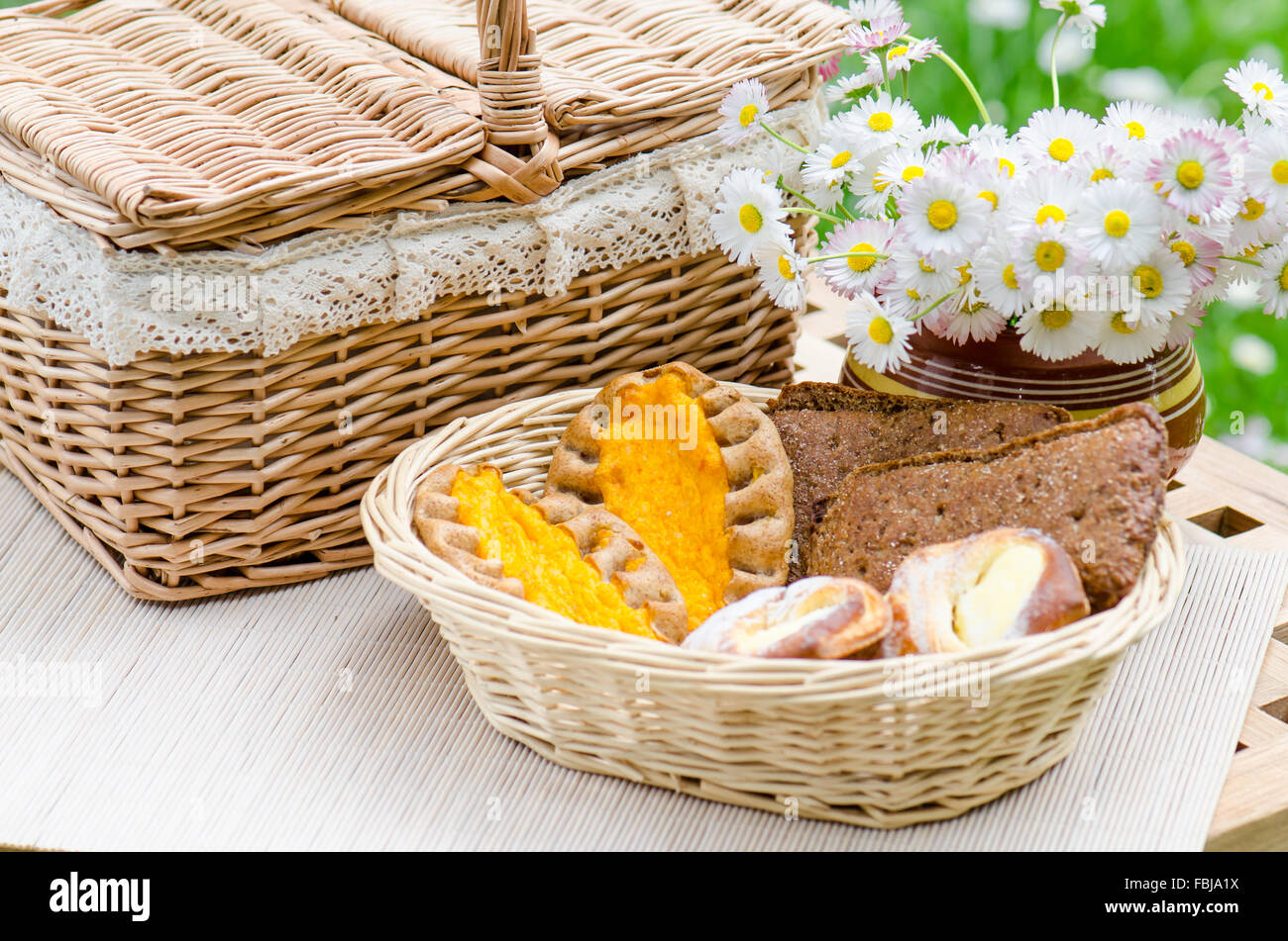 Petits pains dans un panier en osier et un bouquet de fleurs Banque D'Images