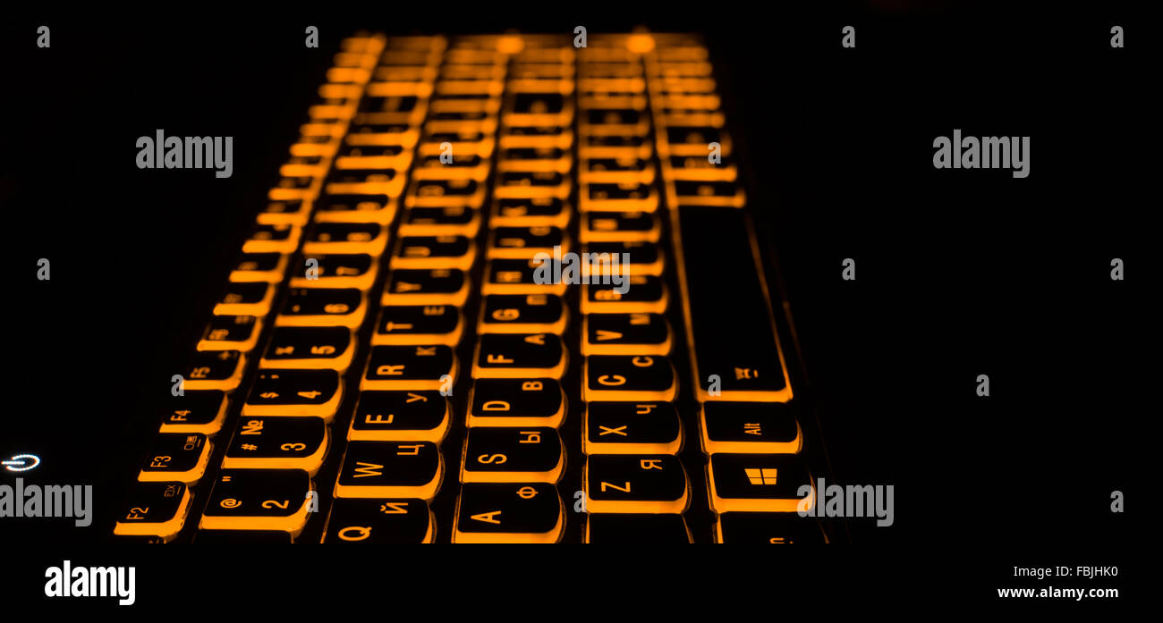 Rétroéclairage du clavier d'ordinateur portable. Lumière chaude et jaune mis sur ordinateur. Fond sombre Banque D'Images