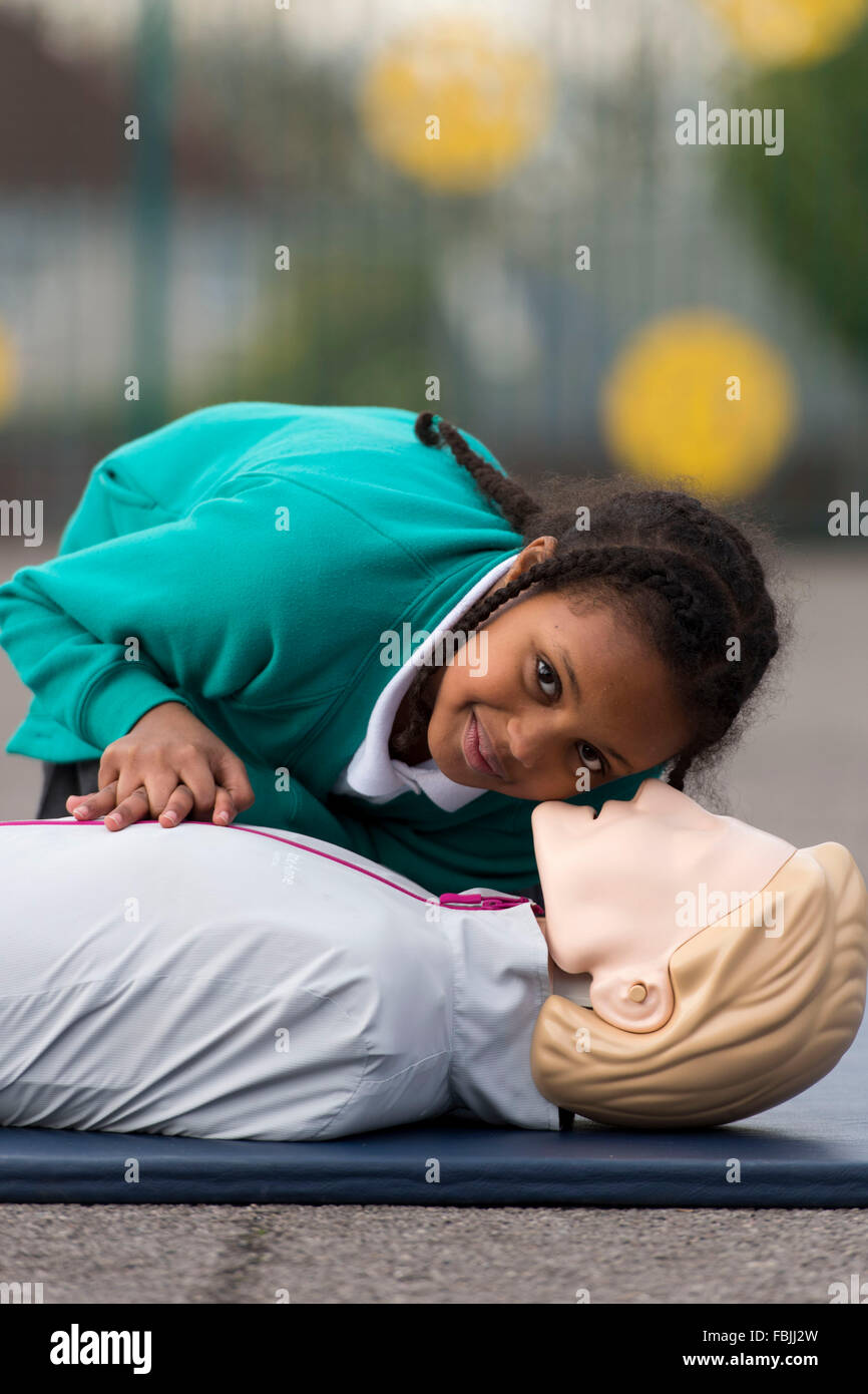La vie d'une écolière apprend les techniques de premiers soins en pratiquant sur un mannequin à l'école. Banque D'Images