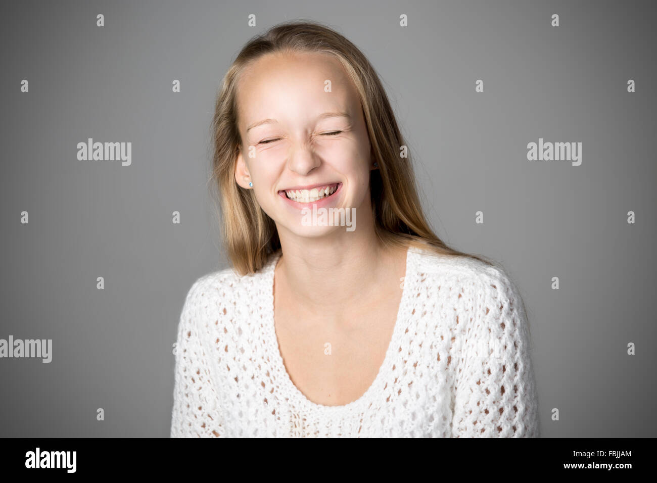 Portrait of happy casual caucasian woman wearing white chandail tricoté, rire avec les yeux clos, studio image Banque D'Images