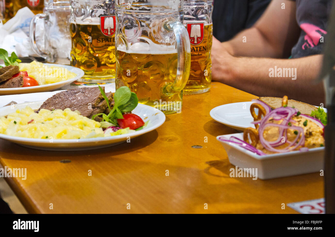 De l'alimentation et de plaques de verres à bière sur une table dans une brasserie à l'Oktoberfest de Munich, en Allemagne. Banque D'Images