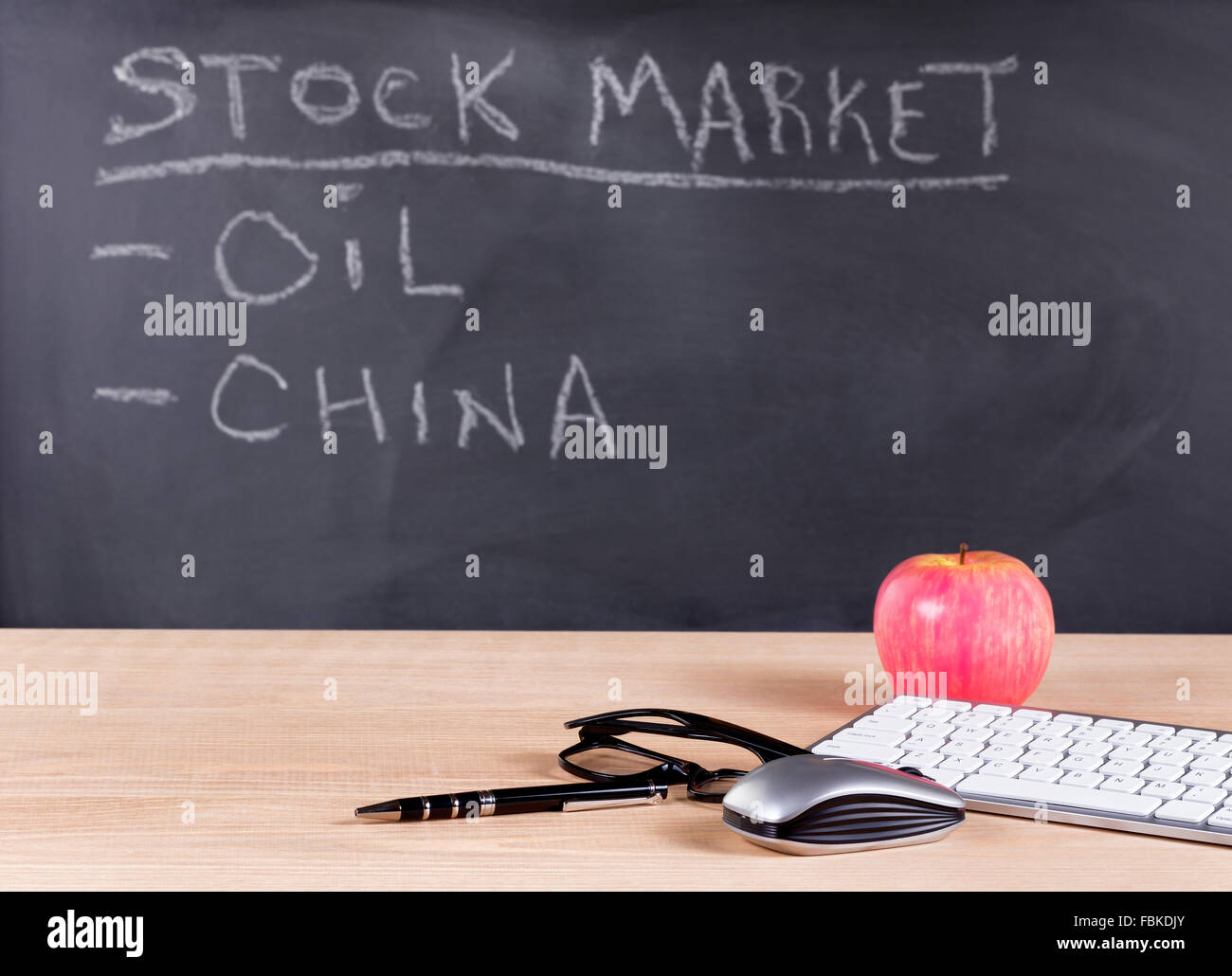 Desktop avec clavier, un stylo, lunettes de lecture, d'une souris et d'Apple. Tableau noir en arrière-plan avec stock market for financial concept Banque D'Images