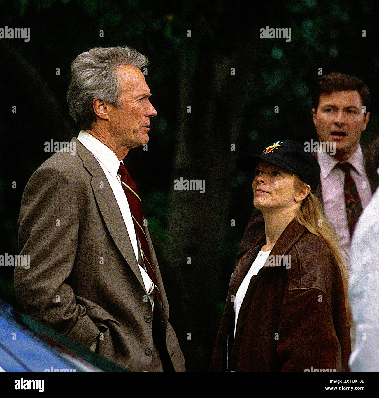 Washington, DC, USA., 12 octobre 1992 Clint Eastwood sur le tournage du film "dans la ligne de feu" de la scène de tournage de l'autre côté de la rue de la maison blanche. ici il parle avec Frances Fisher au cours d'une pause dans le tournage de la scène où eastwood est impliqué dans une poursuite à pied avec le caractère assassin John Malkovich dépeint. debout sur le côté droit est dylan mcdermott qui joue le rôle d'un autre agent des services secrets. crédit : mark reinstein Banque D'Images