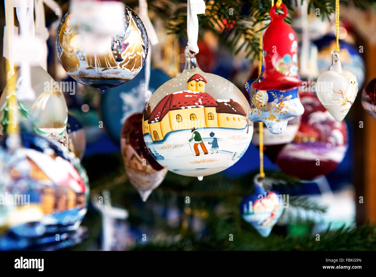 Boule de Noël Boule décorative ou montrant une scène d'hiver suspendu par un ruban dans un marché avec un assortiment d'autres ornements Banque D'Images