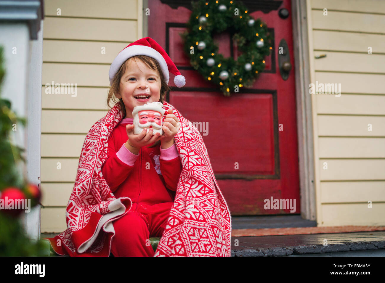 Fille assise sur le porche avant de boire un chocolat chaud à Santa mug Banque D'Images