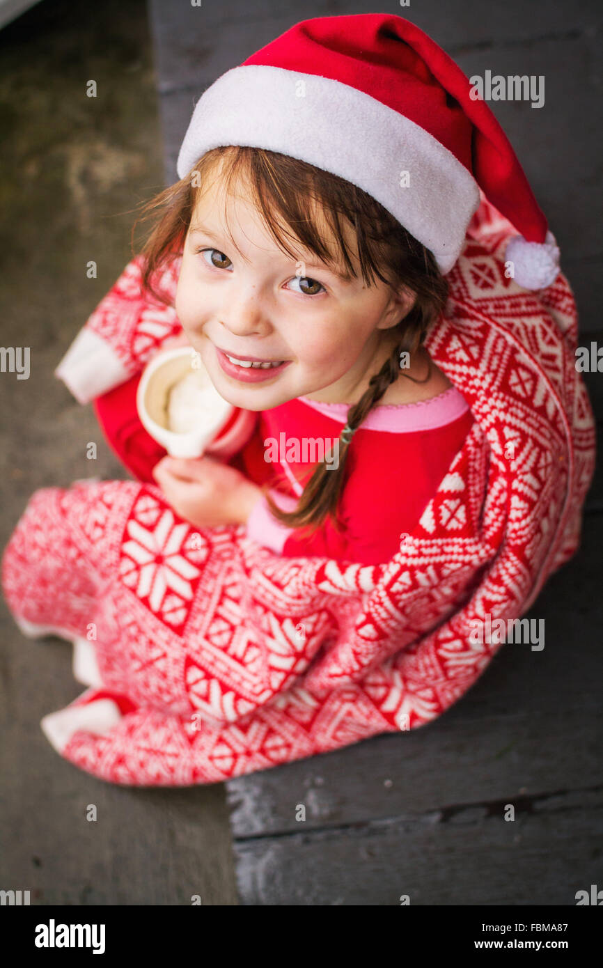 Jeune fille enveloppée dans une couverture de fête, tenant une tasse de chocolat chaud Banque D'Images