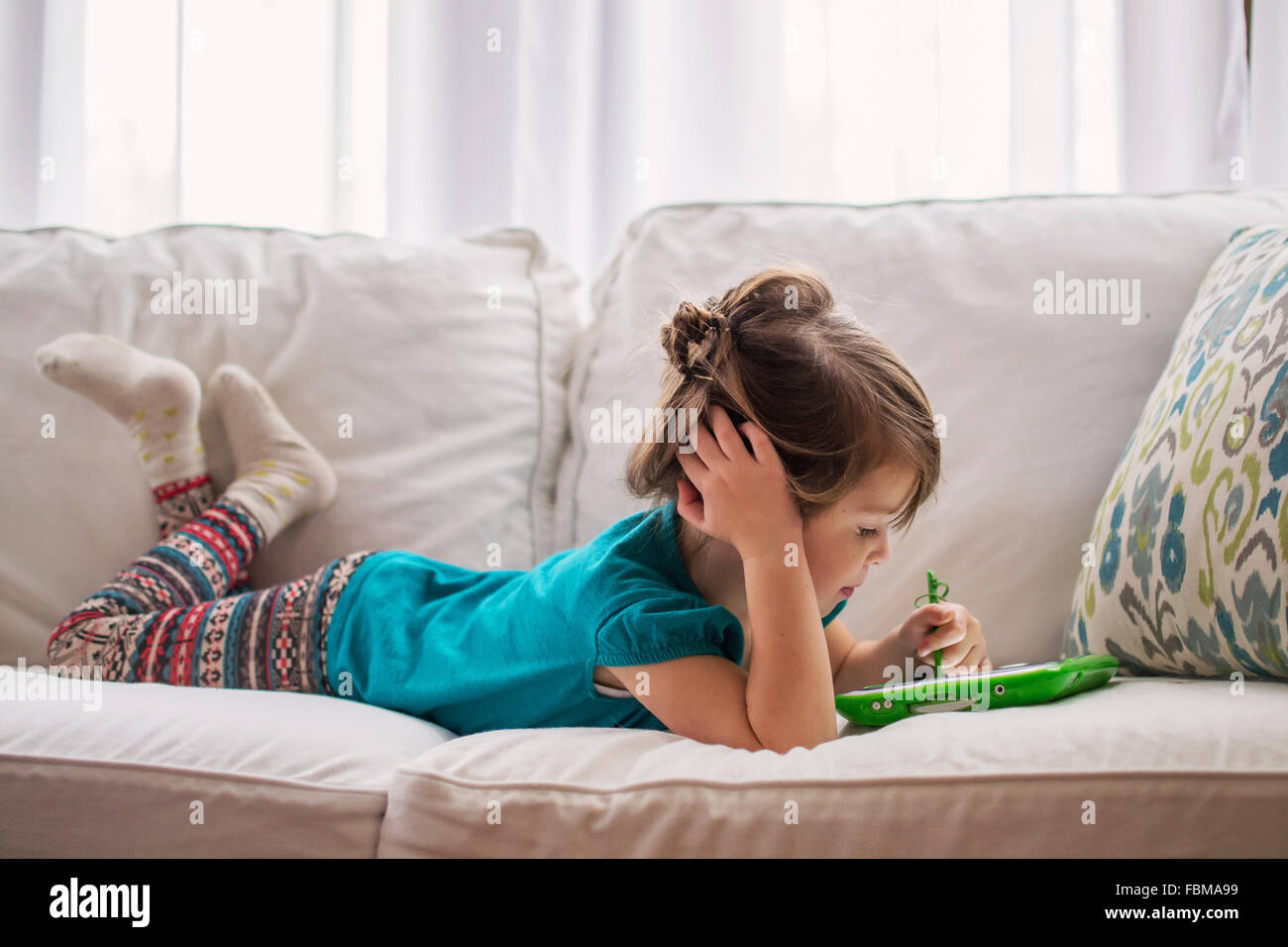 Girl lying on couch Playing with digital tablet Banque D'Images