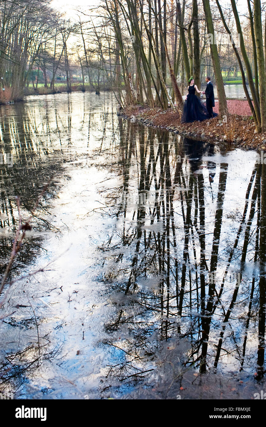 Couple sur le bord du lac avec des réflexions dans l'eau en hiver Banque D'Images