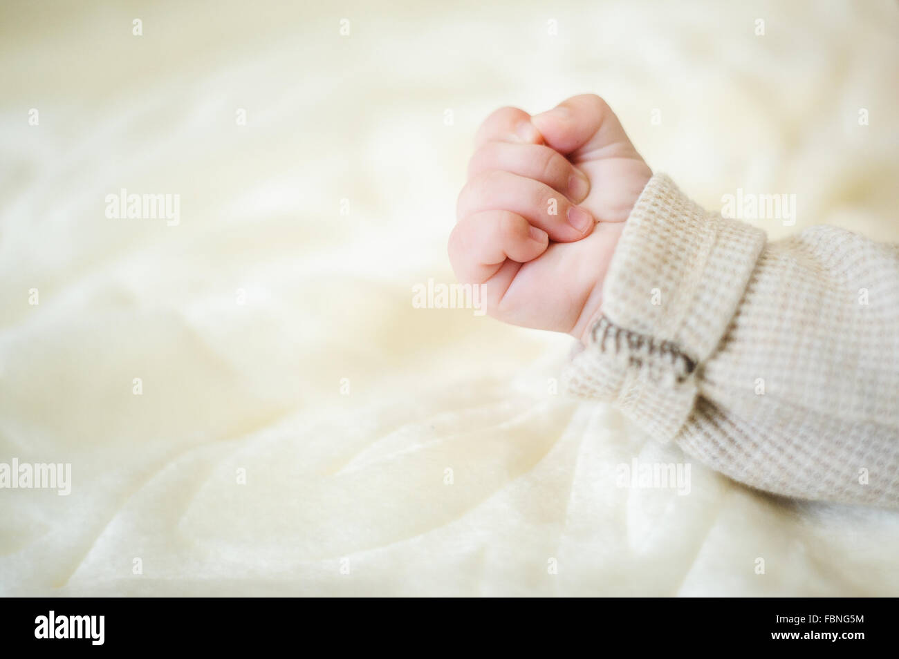La main de bébé et le bras sur une couverture jaune Banque D'Images