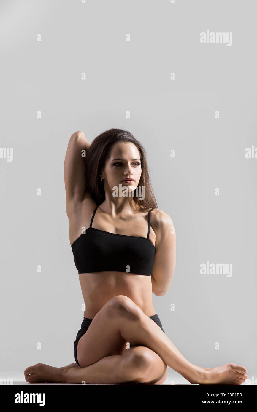 Belle fille yogi sportif pratique le yoga asana, Gomukhasana, vache visage pose, pose de la GC, assis en tailleur Banque D'Images