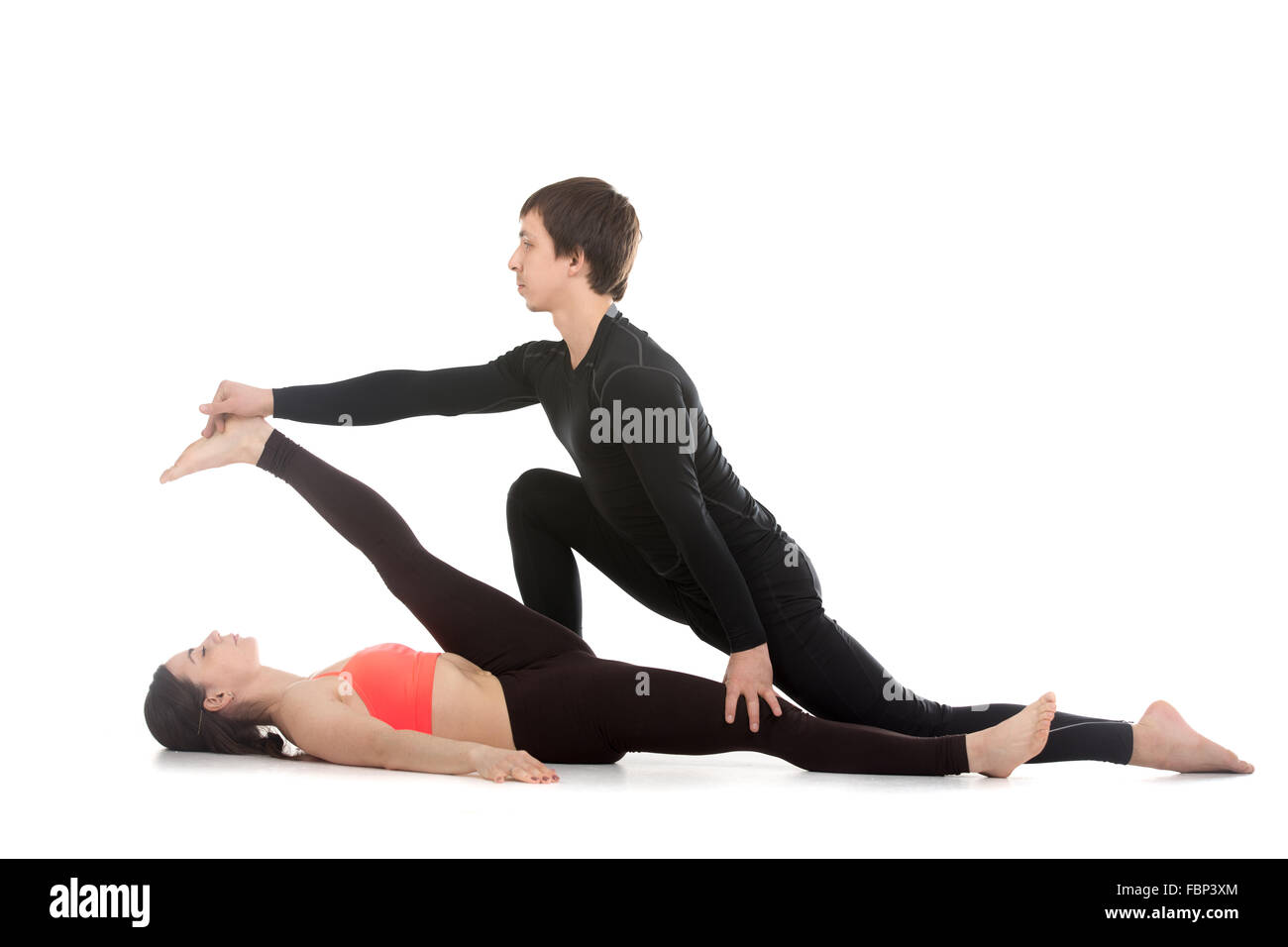 Deux sportifs pratiquant le yoga avec partenaire, jeune homme coaching, aidant à faire fille main inclinables à la posture du gros orteil, supta Banque D'Images