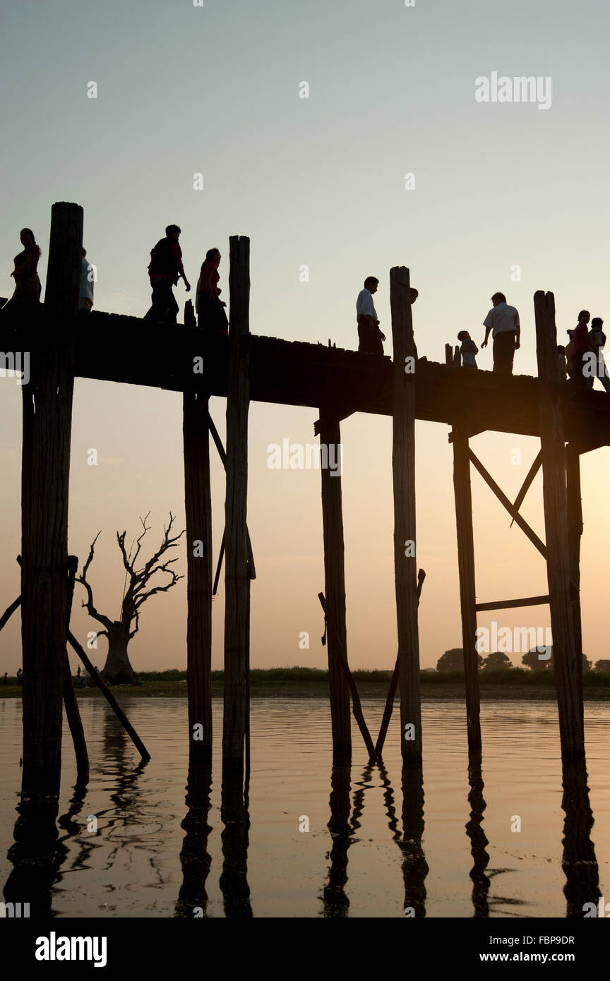 Silhouettes de personnes traversant le pont U Bein dans Amarapura près de Mandalay Myanmar au coucher du soleil Banque D'Images
