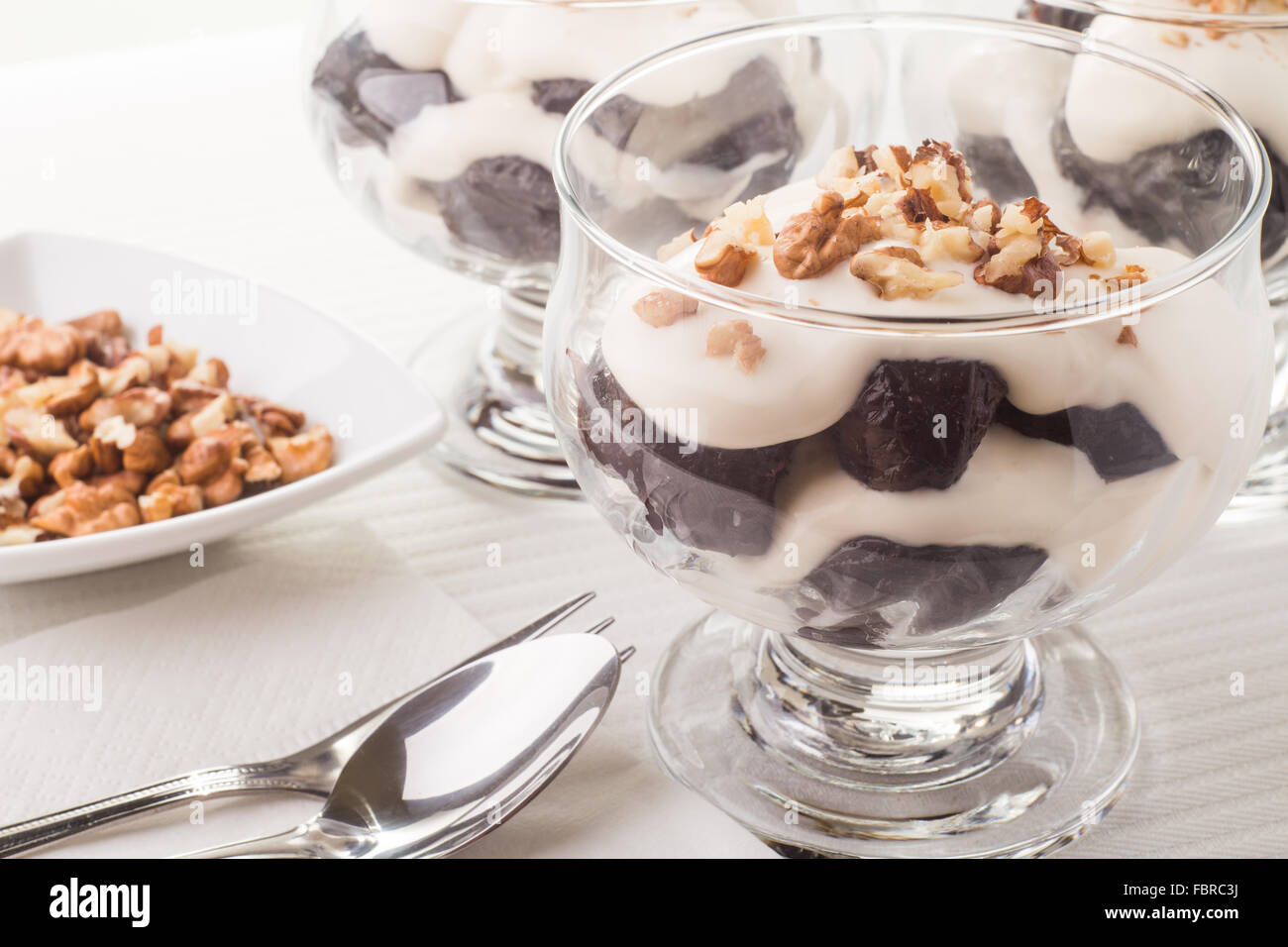 Dessert aux pruneaux, noix et crème fouettée dans verre bowles sur la table Banque D'Images