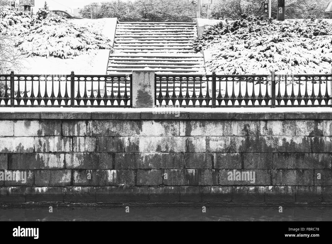 Brique ancienne digue de la rivière avec escaliers en hiver. Image en noir et blanc Banque D'Images