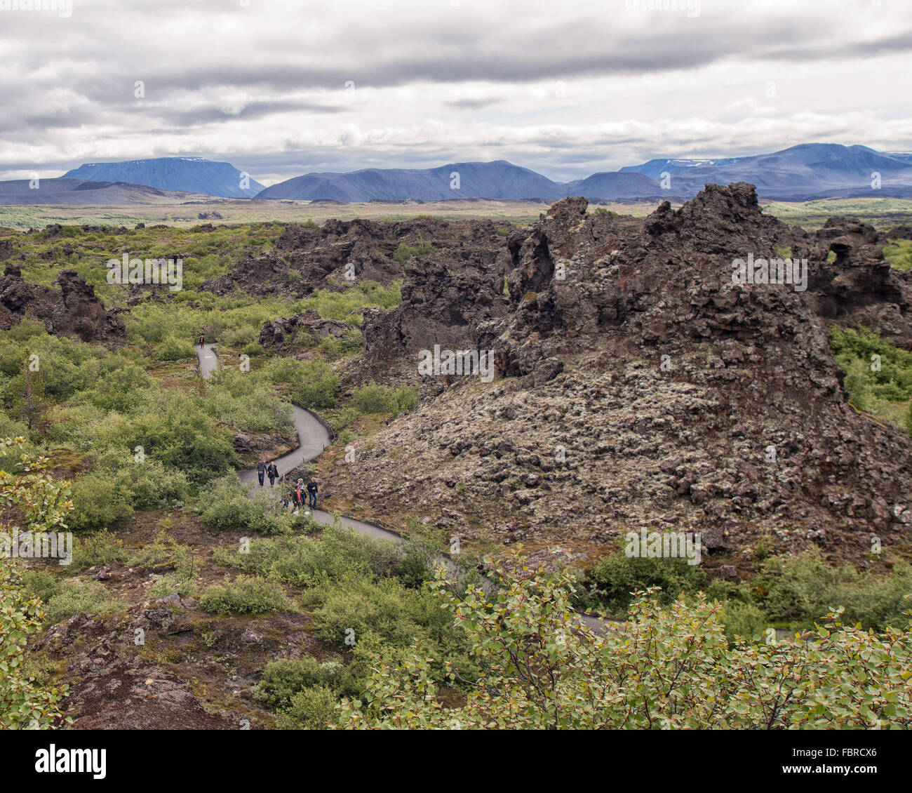 Le nord de l'Islande, Islande. 1er août 2015. Les touristes à pied le long des chemins à travers la circulaire de lave déchiquetées géant de Dimmuborgir (littéralement '' 'l'obscurité des châteaux) au-delà de la forme inhabituelle, piliers et falaises rocheuses atteignant 20m (66 pieds) de hauteur. Réminiscence d'une ancienne citadelle effondrée, ces structures dramatiques, créé il y a environ 2 000 ans par écoulement de lave, à l'Est de l'Islande du Nord en MÃ½vatn, sont l'une des plus populaires attractions touristiques naturelles. © Arnold Drapkin/ZUMA/Alamy Fil Live News Banque D'Images