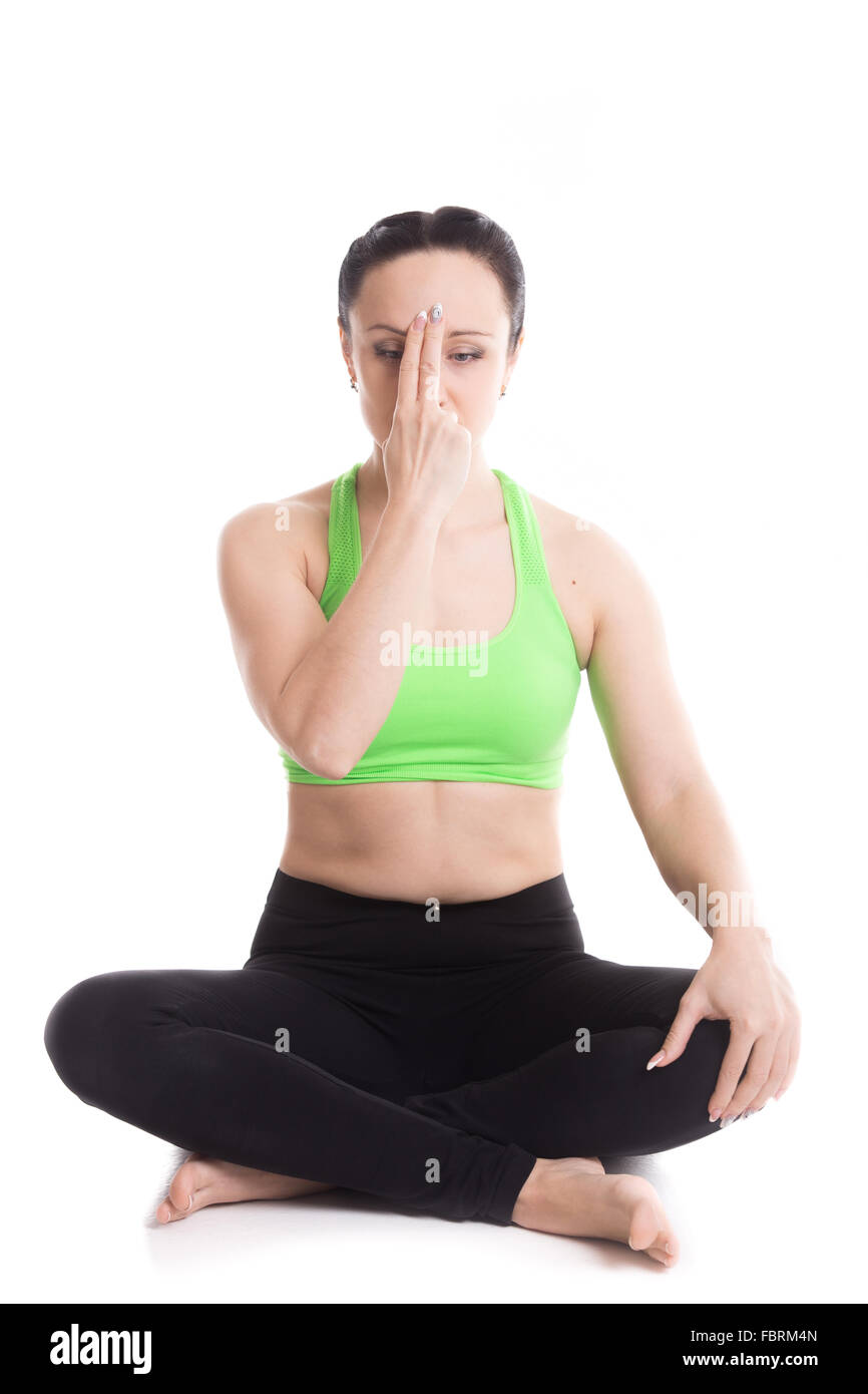 Belle fille sereine nadi shodhana pratiquer le yoga le pranayama (respiration), l'autre narine, assis en pose facile, Sukhasana Banque D'Images