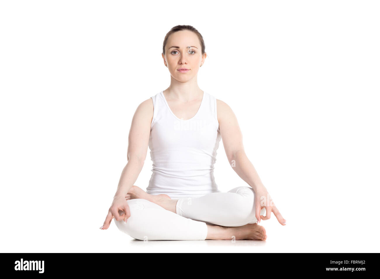 Sporty attractive young woman in white sportswear assis dans Ardha Padmasana, demi-lotus posture, studio vue avant pleine longueur Banque D'Images