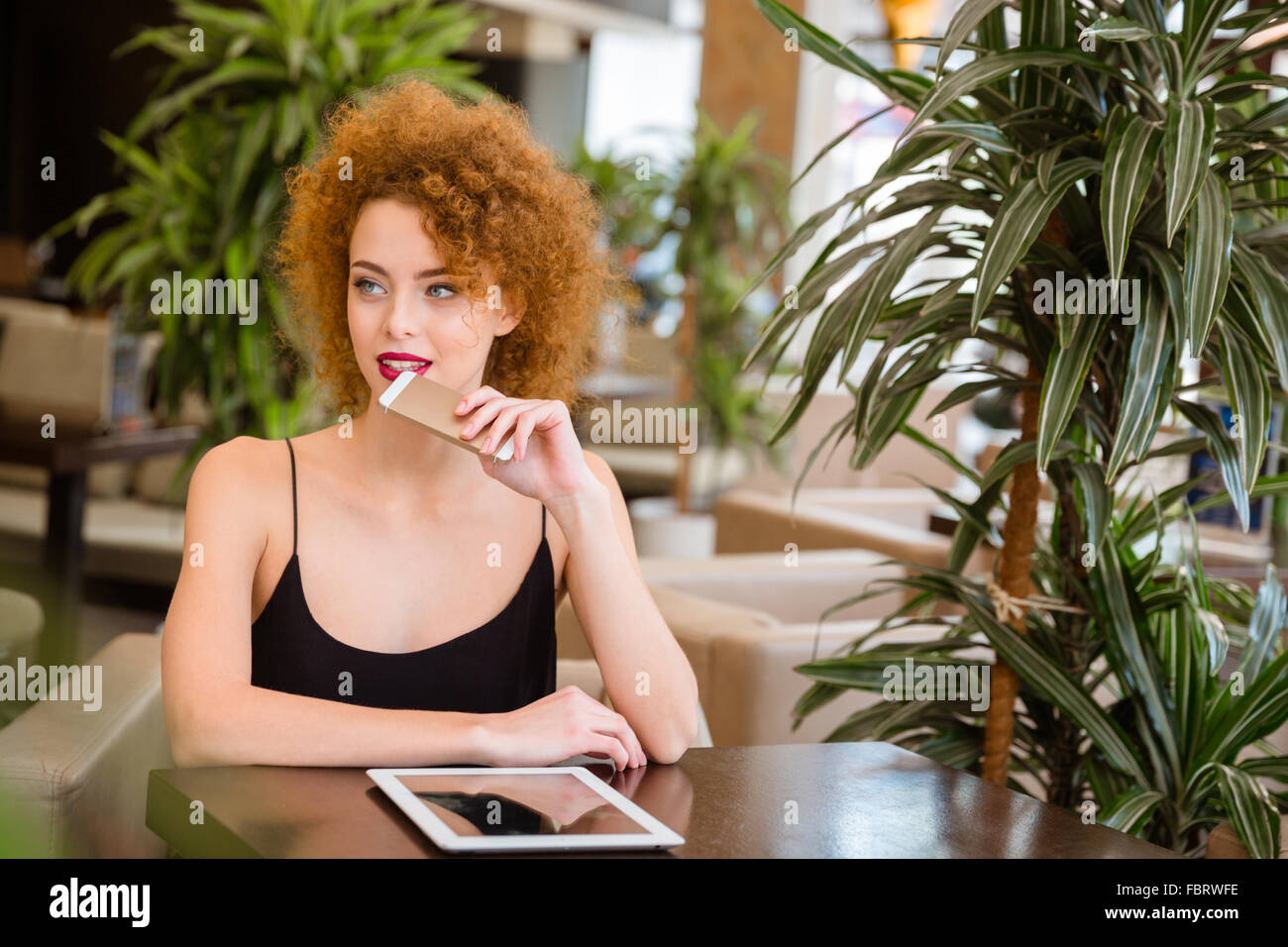 Portrait d'une femme rousse pensive avec des cheveux bouclés sitting in restaurant Banque D'Images