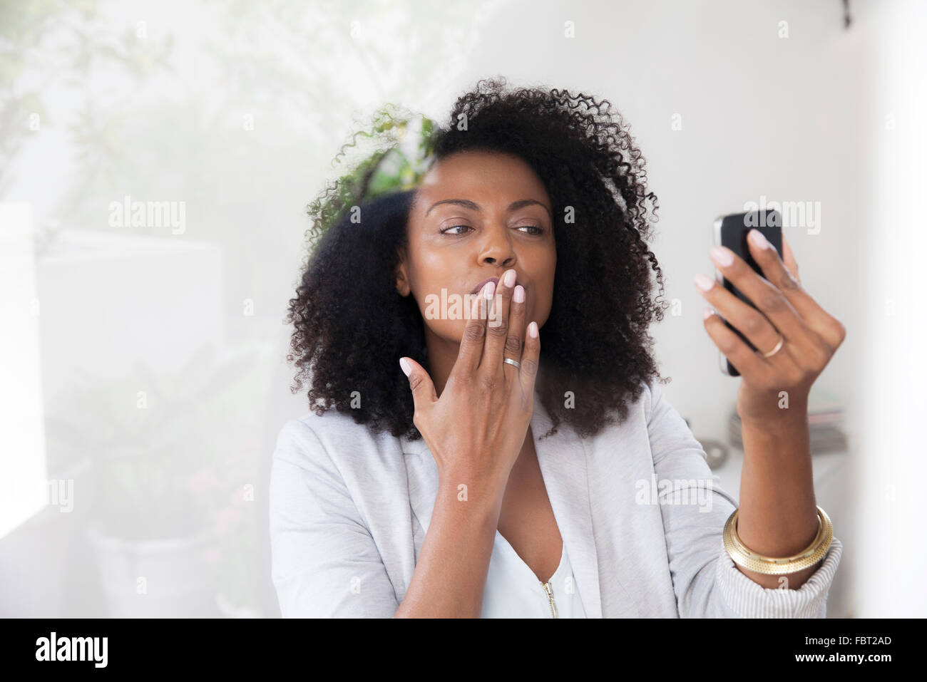 Woman blowing kiss at smartphone tout en faisant du chat vidéo Banque D'Images