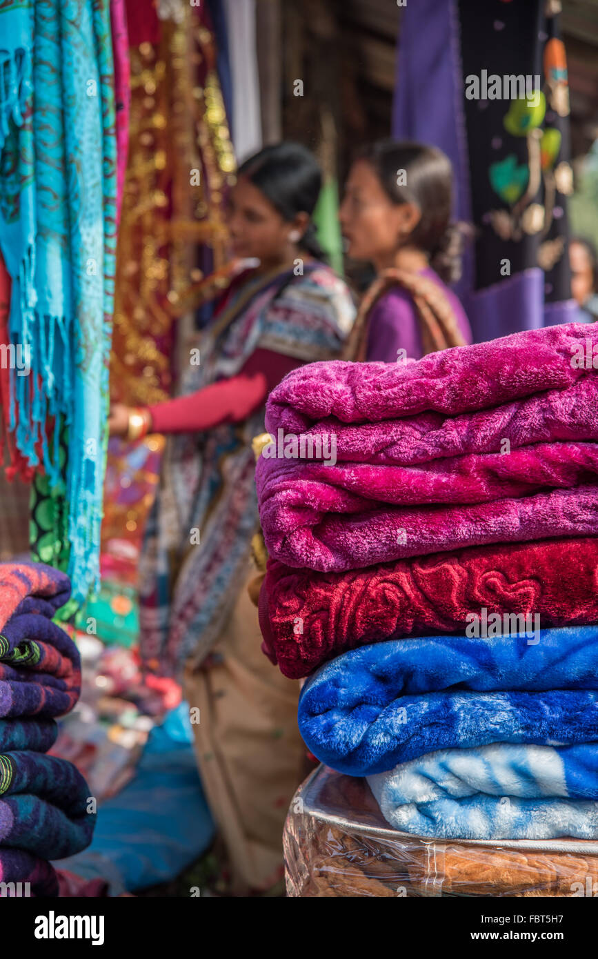 Deux femmes indiennes shopping pour les textiles. Des couvertures dynamiques pour la vente au marché du samedi, près de Balipara Tezpur, Assam, Inde. Banque D'Images