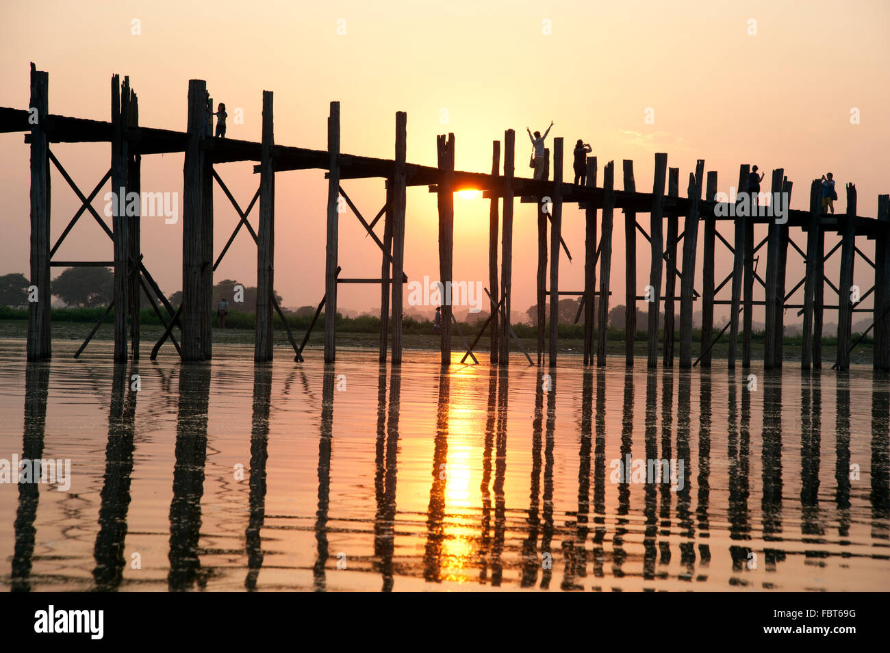 Silhouettes de personnes traversant le pont U Bein dans Amarapura près de Mandalay Myanmar au coucher du soleil Banque D'Images