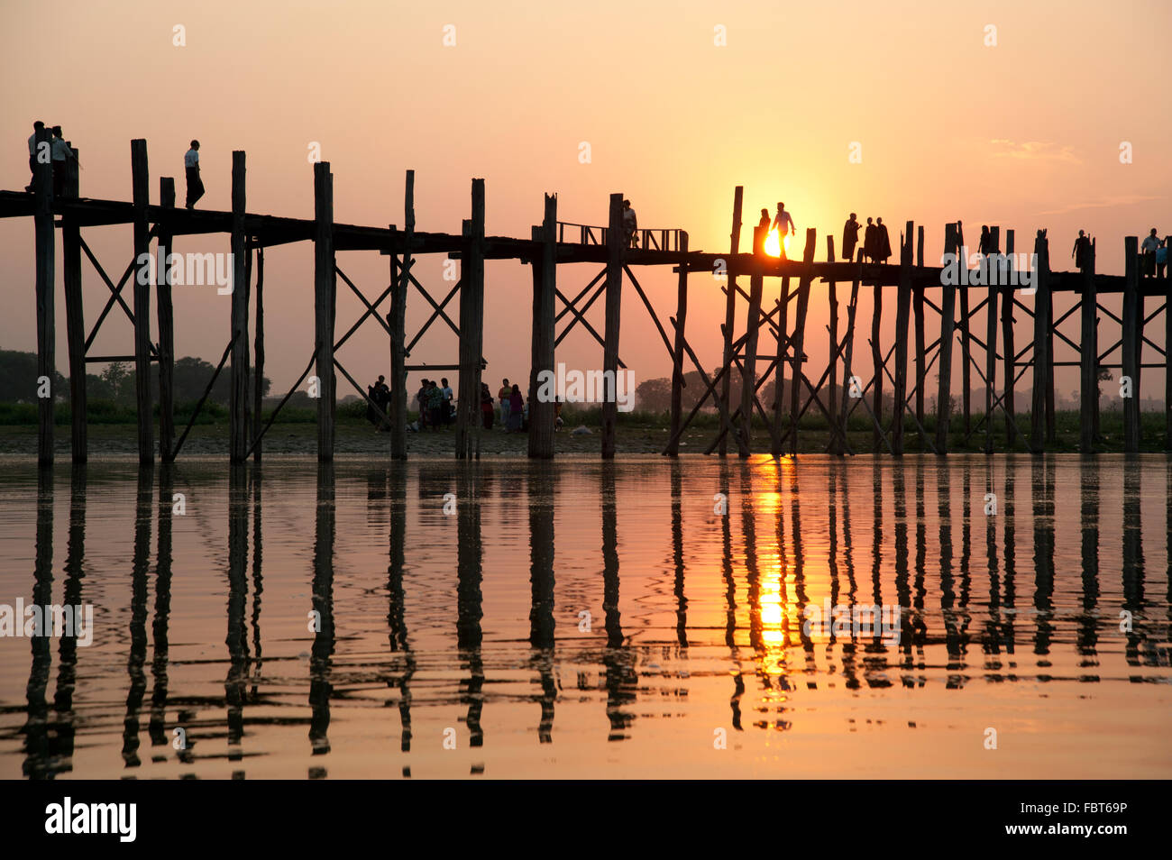 Silhouettes de personnes traversant le pont U Bein dans Amarapura près de Mandalay Myanmar au coucher du soleil Banque D'Images